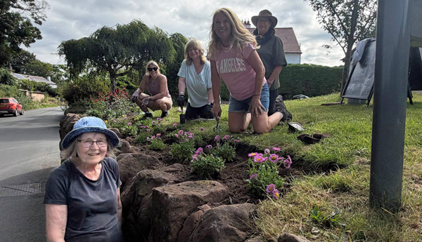 Five women smiling at the camera - by the border
