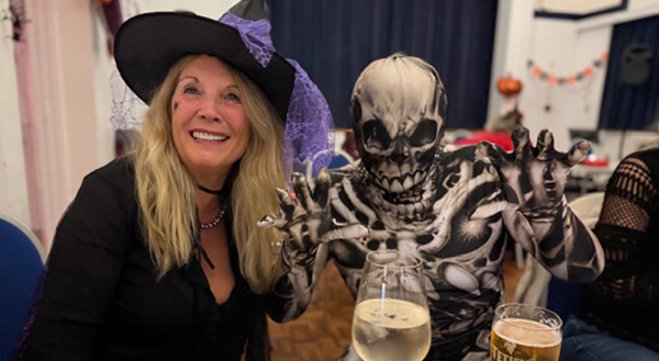 Women dressed as witch sitting next to person dressed as skeleton
